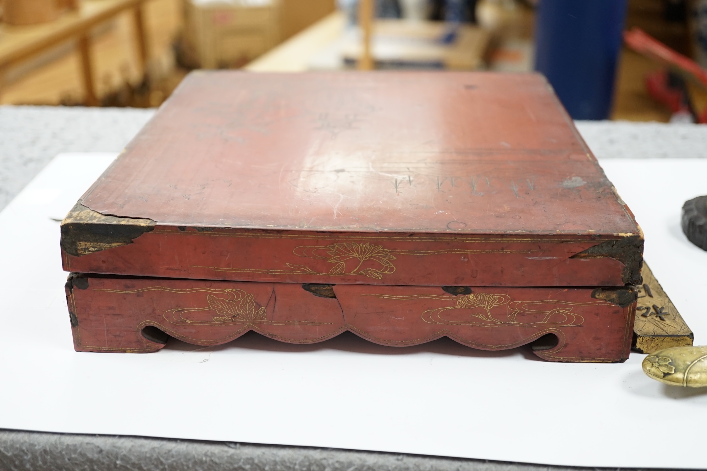 Literati interest: a Chinese red lacquer writing box, 26.5 x 24 x 6.5cm, with two inkstones, a brass paper cutter and ink cake. Condition - fair, some damage to edges and corners of the box